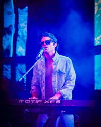 a man in sunglasses playing a keyboard on stage