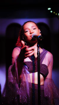a woman in a purple dress singing into a microphone