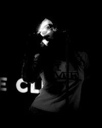 a black and white photo of a woman singing into a microphone