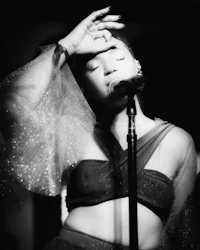 a black and white photo of a woman singing into a microphone